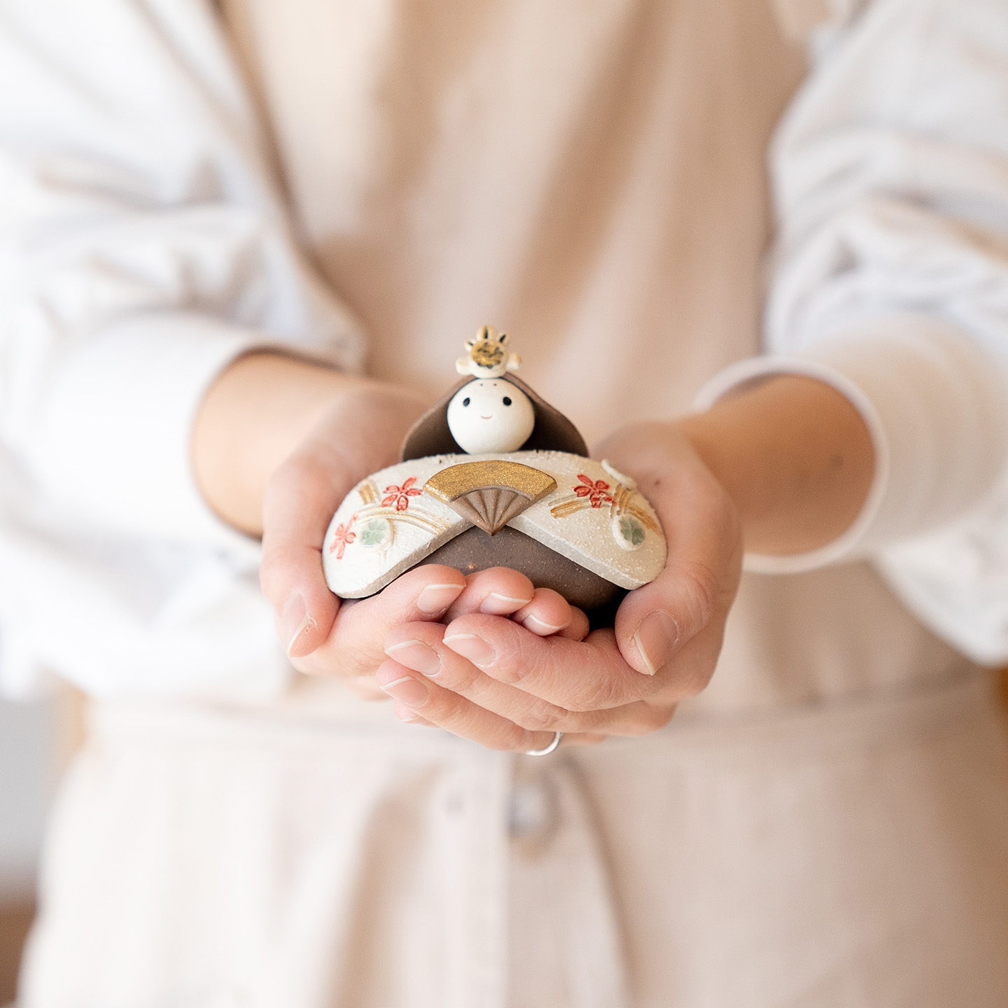 陶器の雛人形を持っている女性