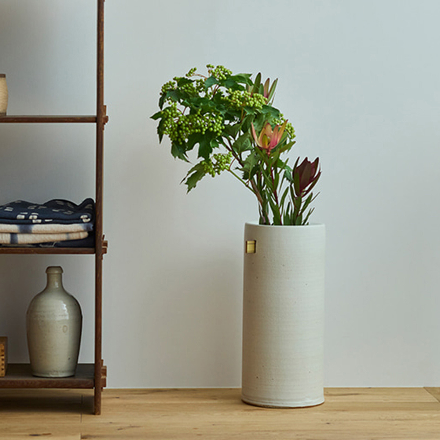 陶器のシンプルな傘立てに植物を生けてリビングに傘っている