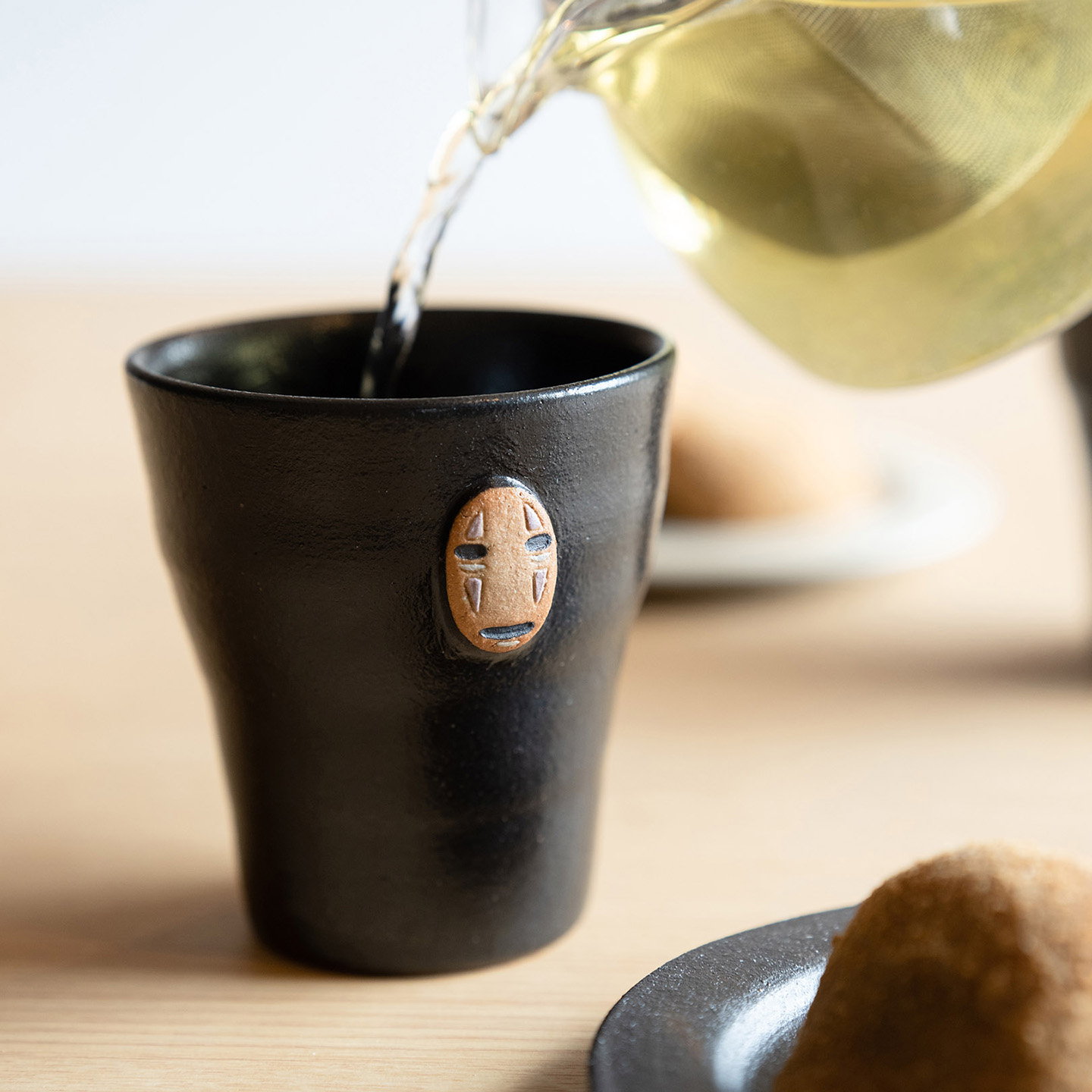 カオナシのフリーカップにお茶を注いでいる