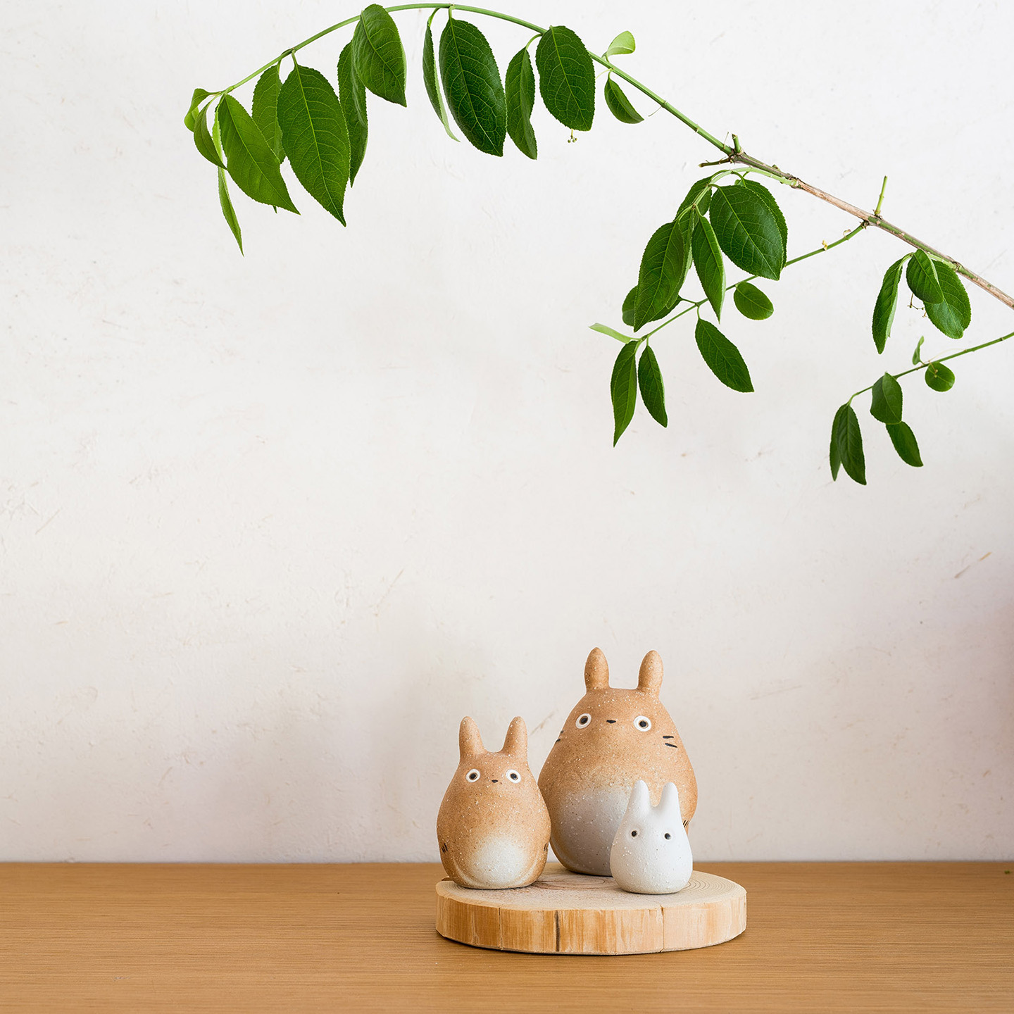 木台に飾られた信楽焼 トトロの3体セットと緑の枝のコーディネート