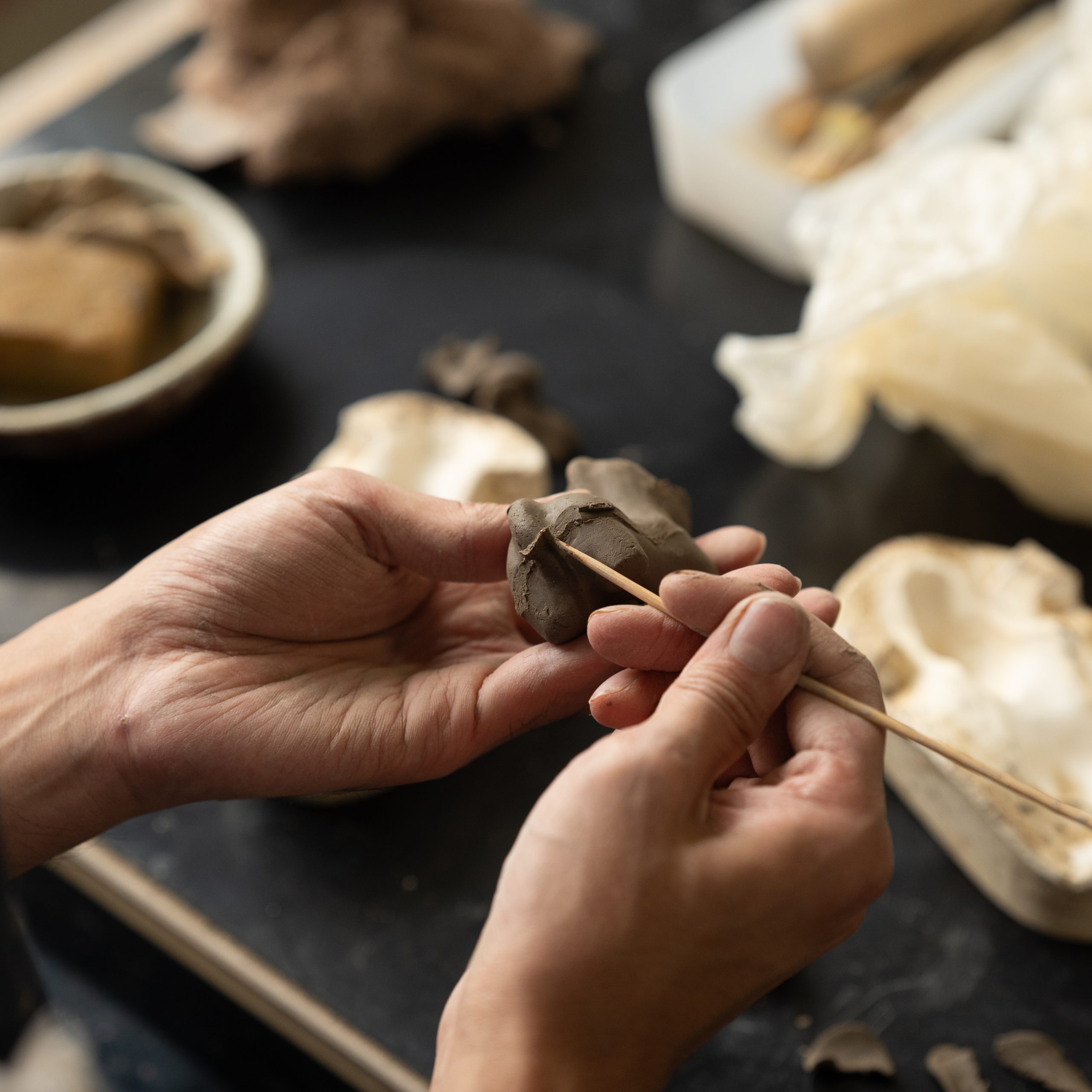 陶器の干支置物「午」を制作している男性の手元