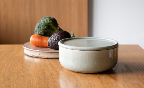 木のテーブルに置かれた陶器のぬか壺と野菜