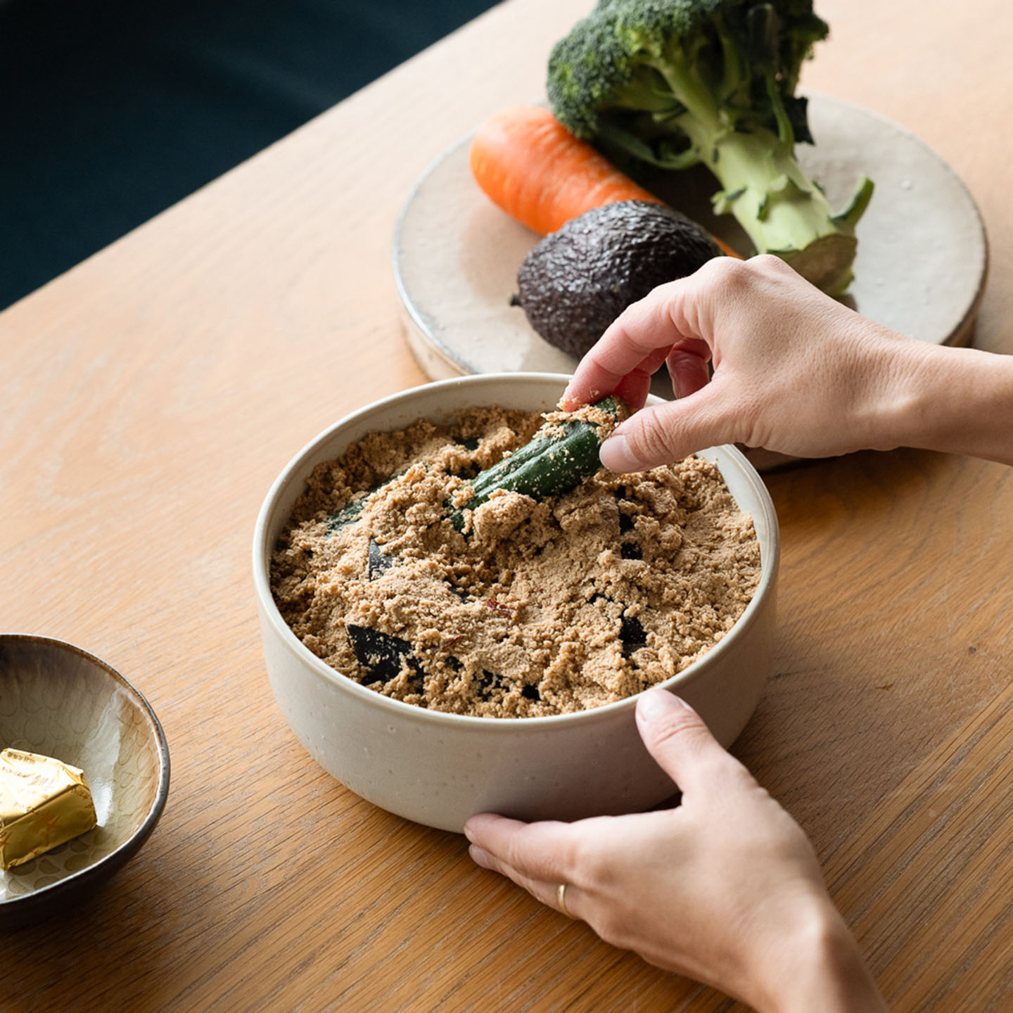 浅型のぬか壺に野菜を漬ける女性の手