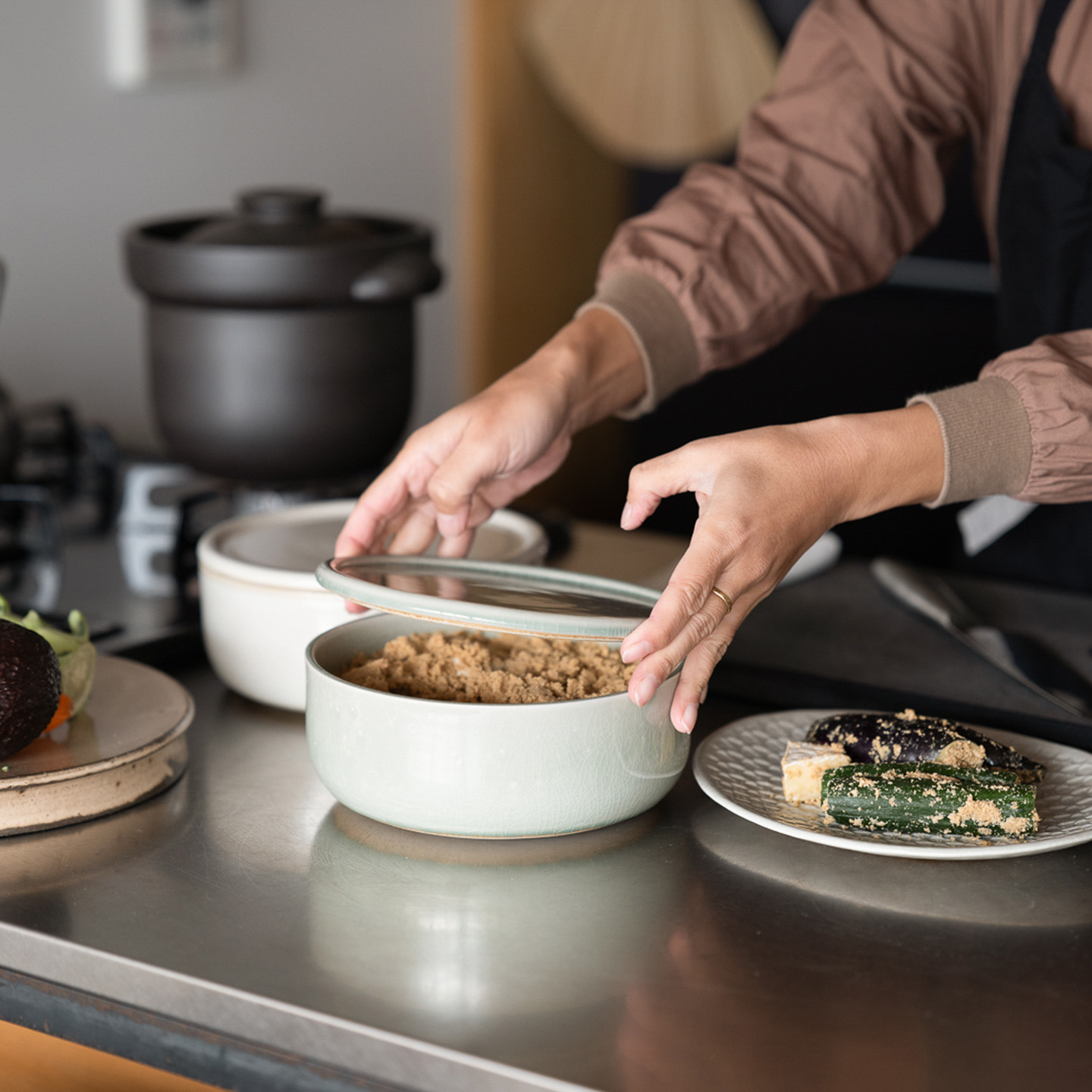 台所で陶器のぬか壺を使用する女性の姿