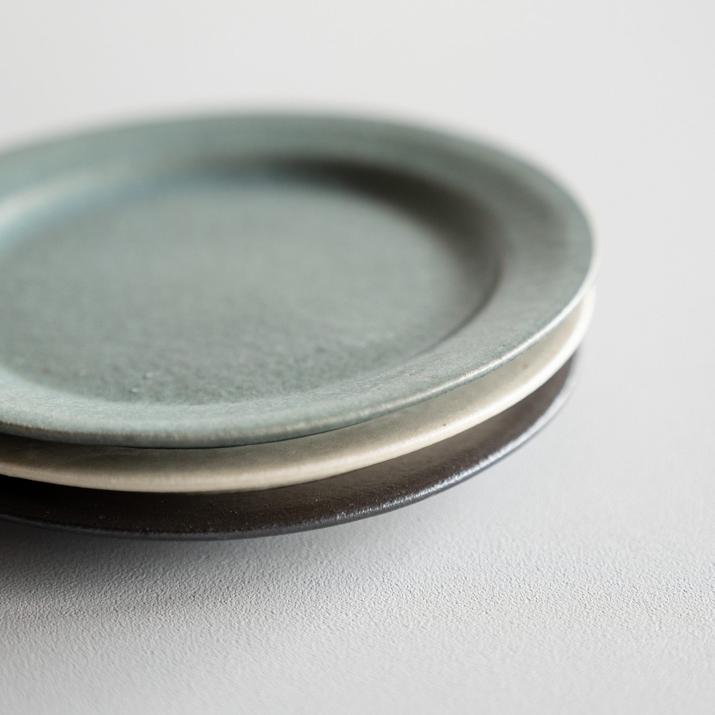 重ねて並べたTEIBAN WAREのリムプレート、食卓になじむ信楽焼のうつわ