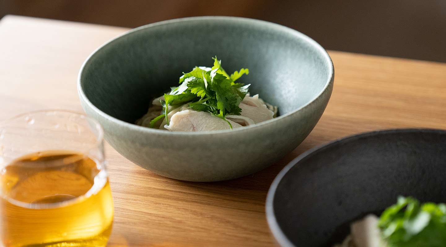 淡い緑色の信楽焼ボウルに盛った冷たい麺料理と、初夏の食卓