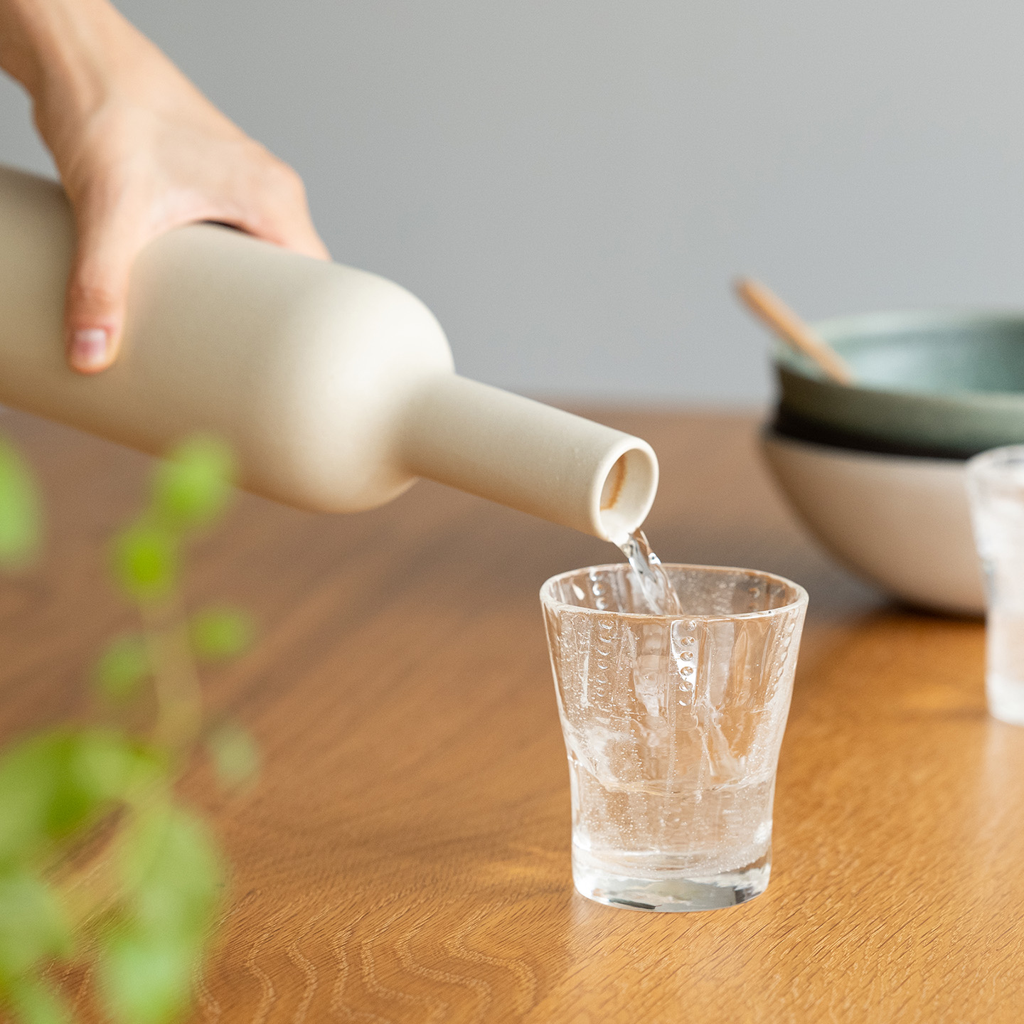 陶器のボトルからグラスへ冷たい水を注ぐ、涼やかな初夏の一場面