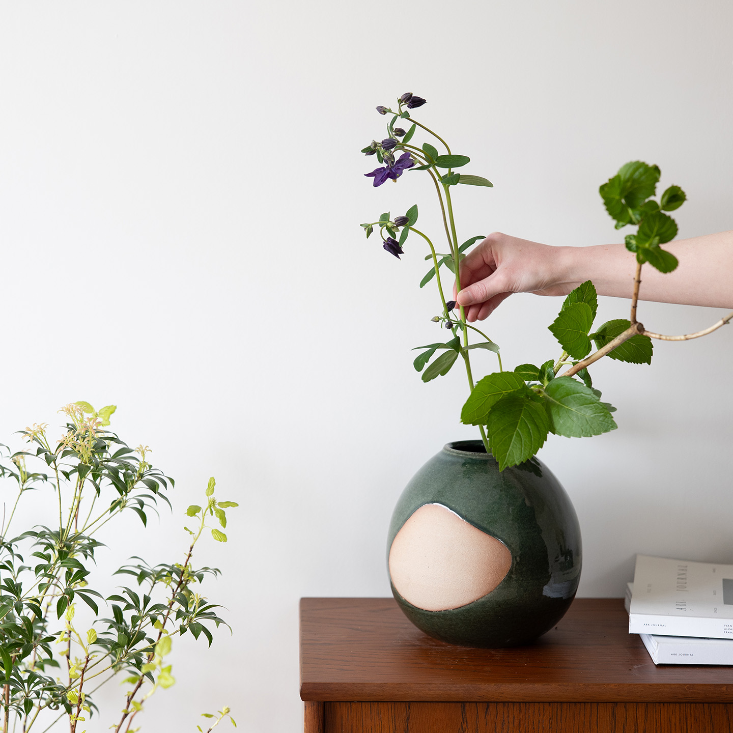 深緑のma花入れに草花を生ける手元